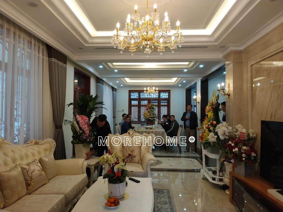 Không gian phòng khách tân cổ điển được bày trí bộ sofa da, đèn chùm, kệ trang trí cao cấp,... thiết kế biệt thự