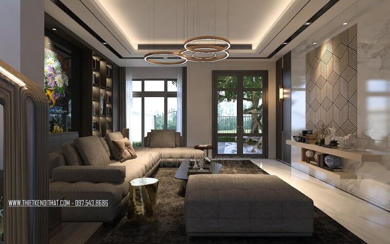 Phòng khách hiện đại sắc trầm nhưng rộng rãi, thông thoáng với cửa sổ, cửa chính kính lớn. Thiết kế phòng khách biệt thự